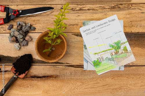 Garden design sketch with garden scissors, flower pot, hand shovel with black soil, gravel on wooden background. Topical garden and home: enthusiast of landscaping and gardening.