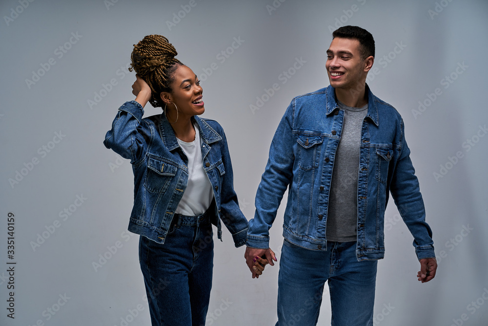 Happy girl with a guy in denim jackets and jeans walk holding hands. Relationship concept Happy girl with a guy in denim jackets and jeans walk holding hands. Relationship concept
