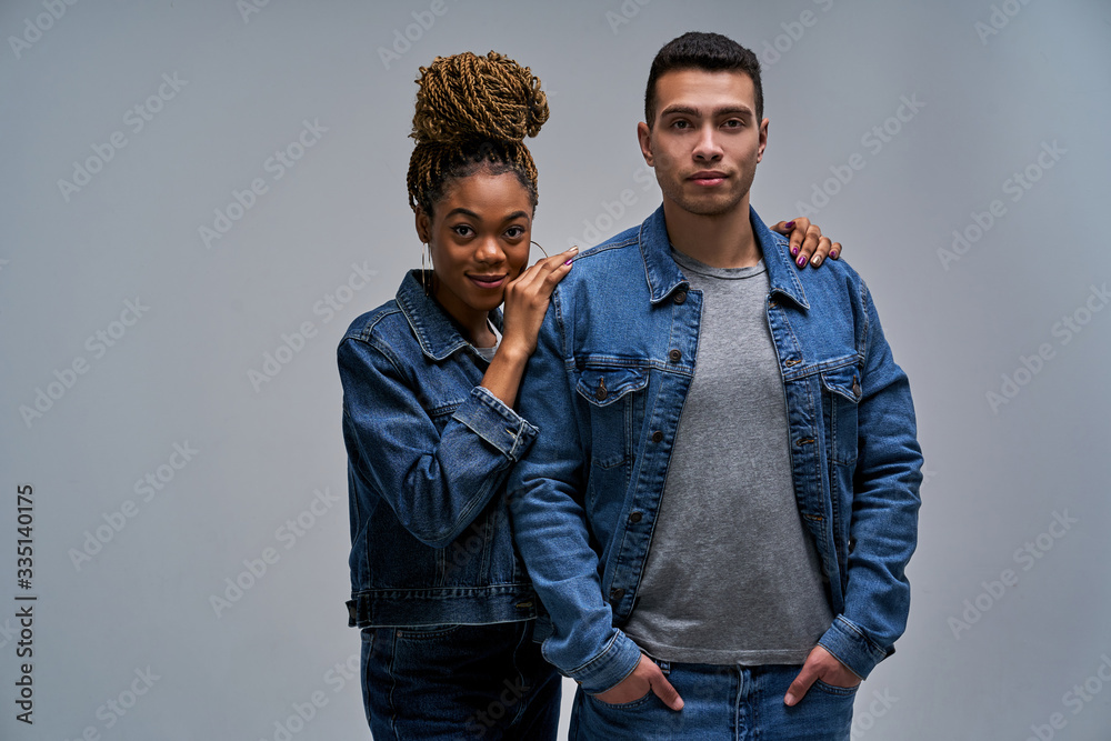 Happy girl hugs a man with arms over his shoulders in denim jackets in jeans. Relationship concept Happy girl hugs a man with arms over his shoulders in denim jackets in jeans. Relationship concept
