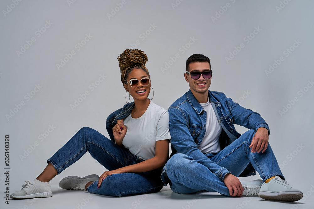 Φωτογραφία Happy girl and guy in denim jackets in sneakers in jeans are sitting on the floor