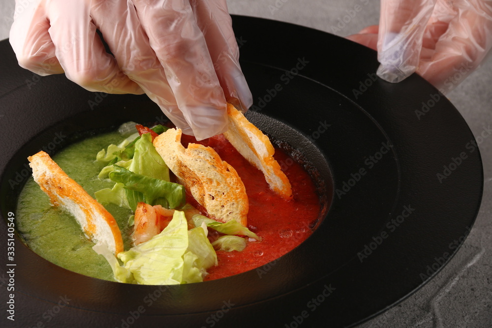 tomatoes soup with hands. chef decorating plate. kitchen processing