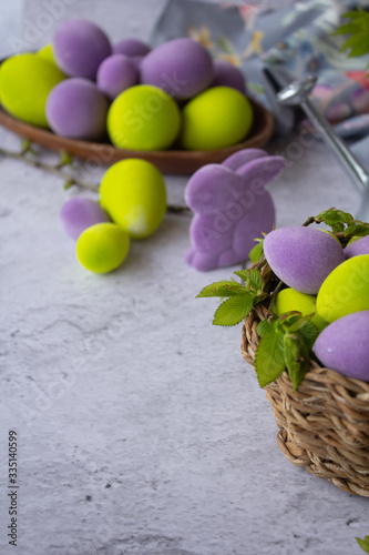 easter green and purple eggs with rabbit on a light surface