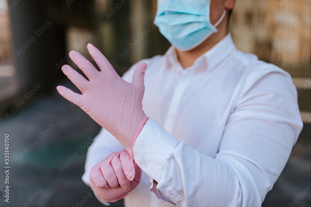 
A man in a white shirt with a mask on his face is wearing gloves. Protection from COVID - 19