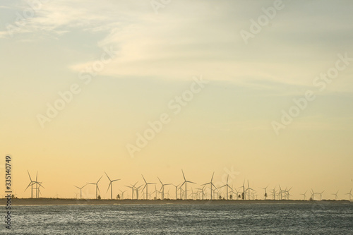 Turbines of wind power on the sunset on the beach