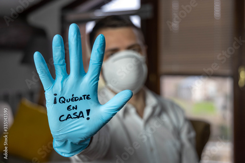 Young man with open palm with a glove and a mask written in Spanish 
