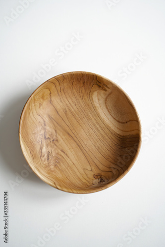 Wooden utensils for food on a white isolated background. Handcrafted natural bowl plates from an expensive variety of wood. Empty round tray. Eco-friendly cookware.