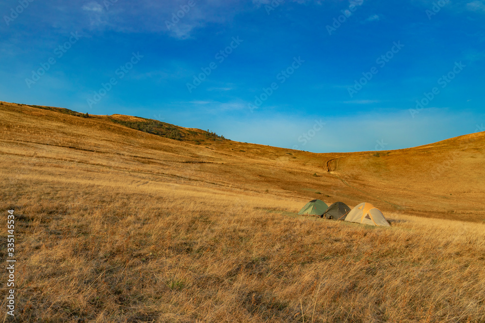 travel life style landscape picture of tent camp site in highland mountains plateau space yellow grass cover ground surface and blue sky