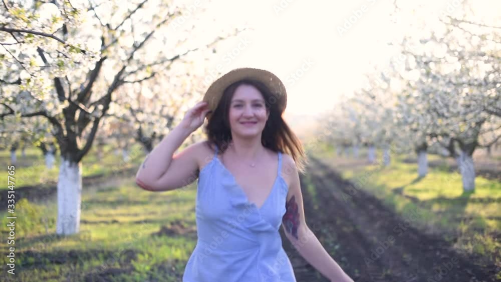 Cheerful girl with brunette hair in hat holds blossom brunch at the sunset Cheerful girl with brunette hair in hat holds blossom brunch at the sunset