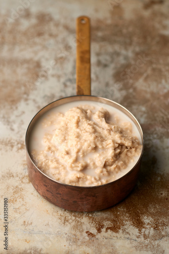 Cooked Oatmeal in Copper Saucepan on Weathered Stainless Steel Surface