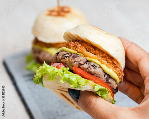 Women's hands holding a healthy vegan burger made with bean meat