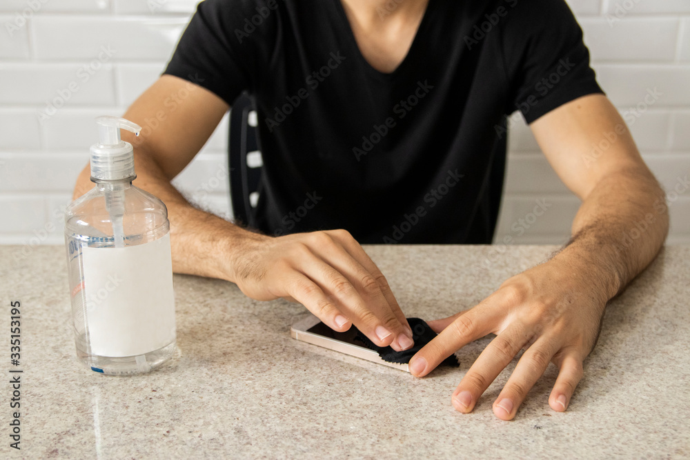 Coronavirus prevention. Man using alcohol gel to clean mobile smartphone. Hygiene concept. Novel coronavirus. (2019-nCoV). Covid-19.