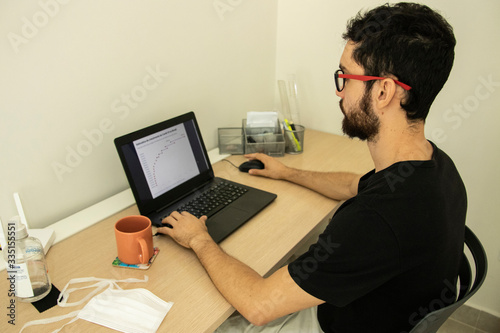 Man on laptop following the Brazil news and graphics about Coronavirus. Portuguese language. Coronavirus concept. Novel coronavirus. (2019-nCoV). Covid-19.