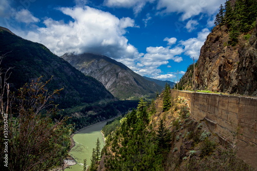 Fraser river in narrow gorge, The Trans Canada Highway runs along the Canyon. On one side of the road are sheer cliffs on the other, a deep canyon at the background of mountain range and blue cloudy