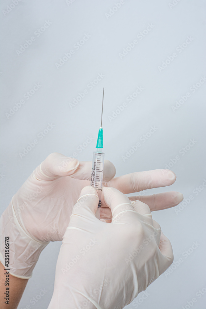 Syringe held by hands with white latex gloves Syringe held by hands with white latex gloves