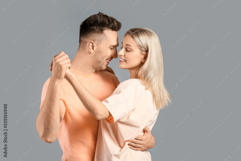 Happy dancing young couple on grey background Happy dancing young couple on grey background
