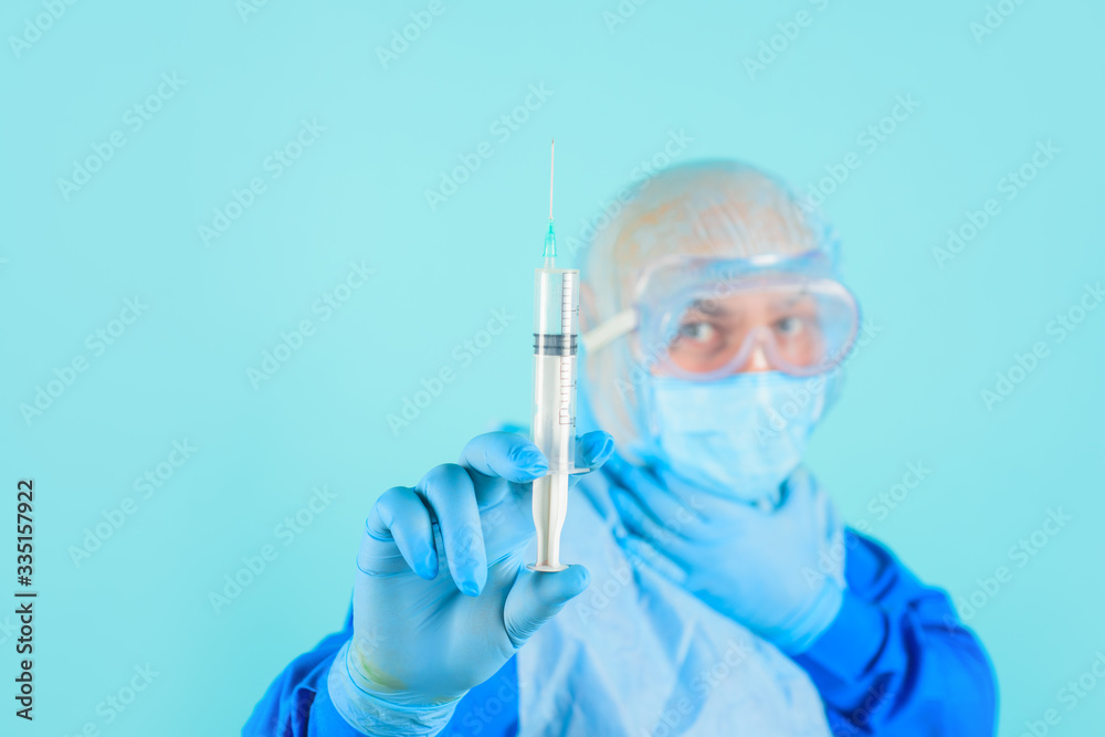 Male nurse preparing for injection. Doctor in protective suit, goggles and medical mask with syringe makes virus vaccination in medical center. Male doctor in mask with syringe. Male nurse preparing for injection. Doctor in protective suit, goggles and medical mask with syringe makes virus vaccination in medical center. Male doctor in mask with syringe.