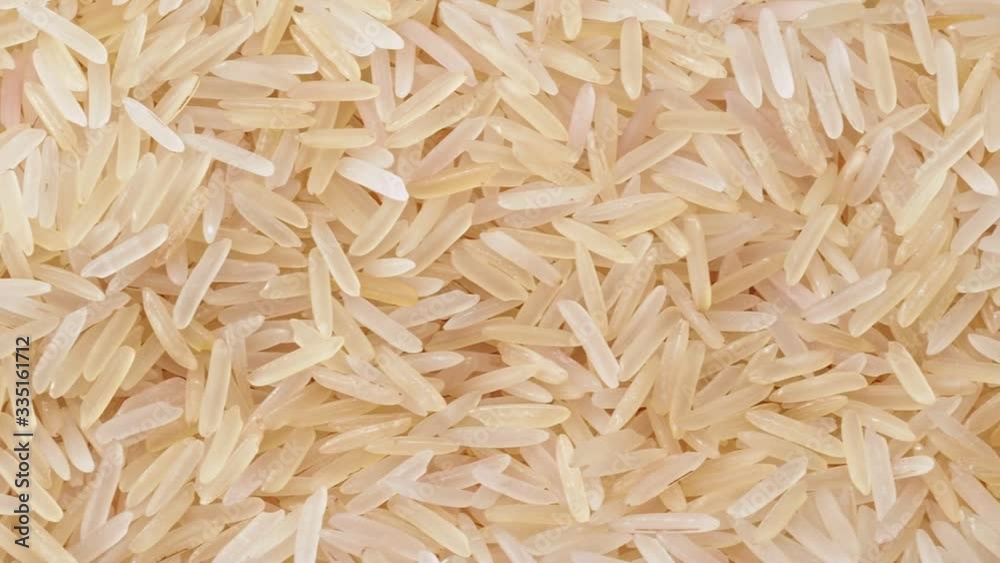 Uncooked white long rice, close shot. Dolly shot of heap of white rice. Texture of rice, abstract background. Selective soft focus. Blurred background Uncooked white long rice, close shot. Dolly shot of heap of white rice. Texture of rice, abstract background. Selective soft focus. Blurred background