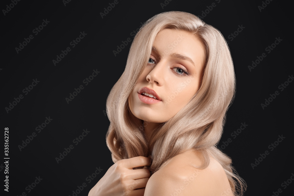 Fototapeta premium Young blonde with beautiful hair on dark background