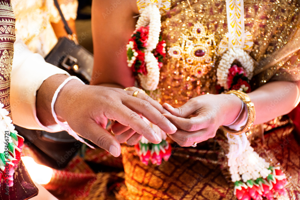 Thai bride and groom in Ceremony wearing a wedding ring of marriage celebration thai style at retro home in countryside of Yasothon, Thailand