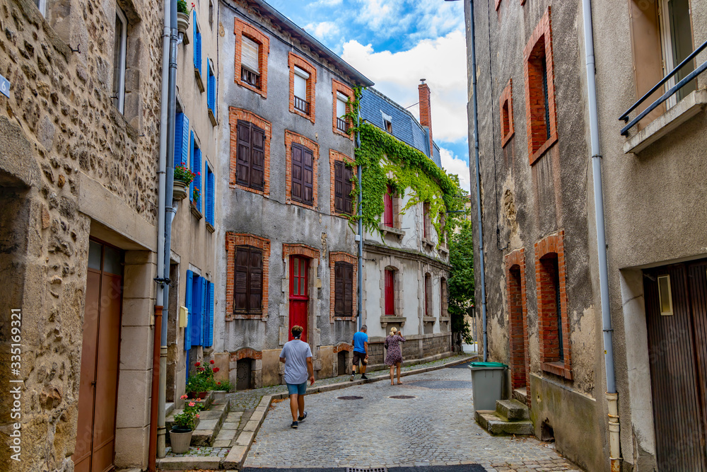 Tourists walk along a picturesque street in France.