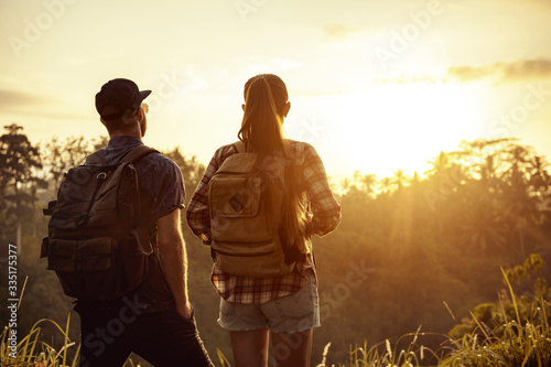 Couple travelers with backpacks looks at sunrise