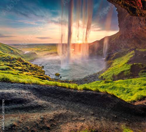 Populaк tourist destination - Seljalandsfoss waterfall, where tourists can walk behind the falling waters. Spectacular summer scene of Iceland, Europe. Beauty of nature concept background.