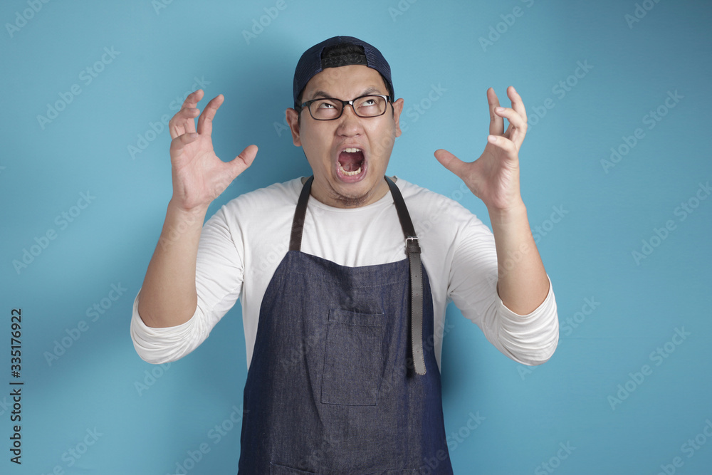 Naklejka premium Portrait of Asian male chef or waiter screaming loud, stress tired of work
