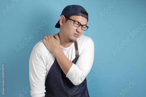 Portrait of male Asian chef or waiter suffer from neck pain, tired expression