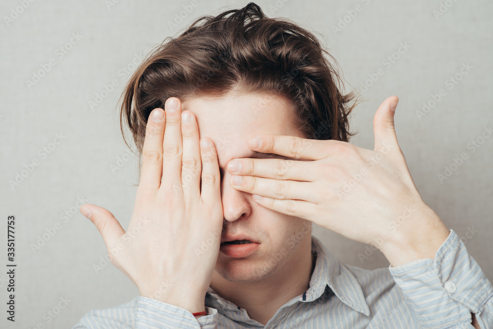 young man closes his eyes with his hands young man closes his eyes with his hands