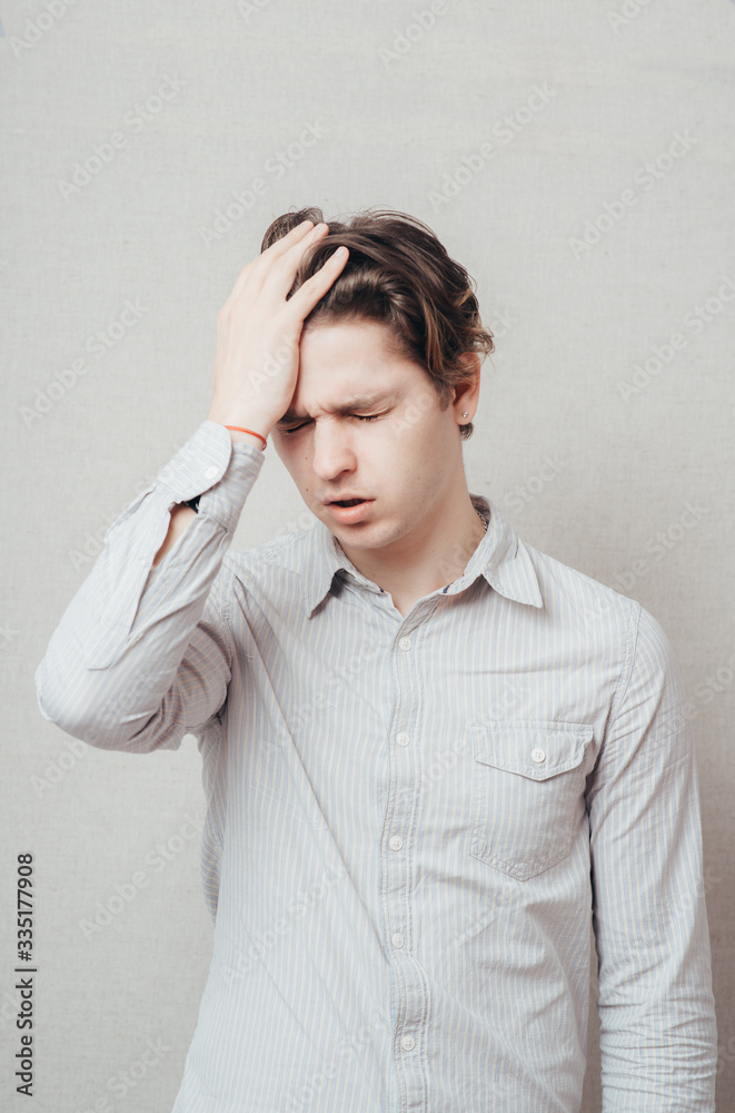 Closeup portrait of a upset young man with hand on his head Closeup portrait of a upset young man with hand on his head