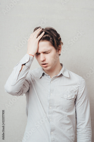 Closeup portrait of a upset young man with hand on his head