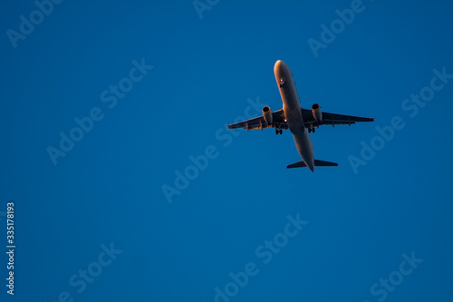 A plane flies through the blue sky