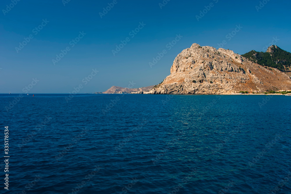 Large stone cliff on the shore of the blue sea
