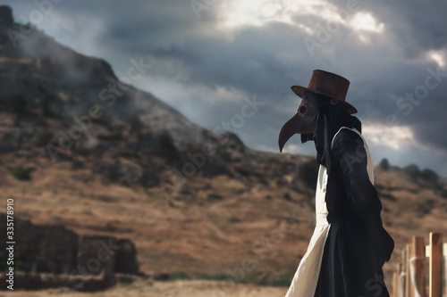 Canvas Print A man in historical masquerade costume of plague doctor in old gothic grange building of church