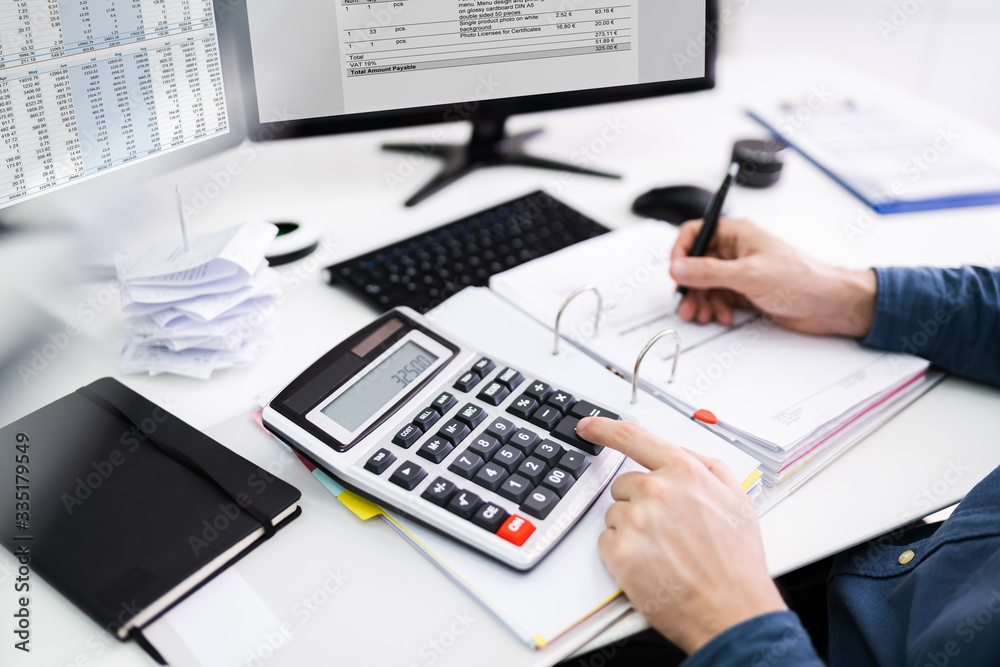 Young Businessman Calculating Bill In Office
