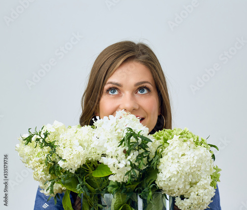  woman holding white flowers in front of face and looking up.