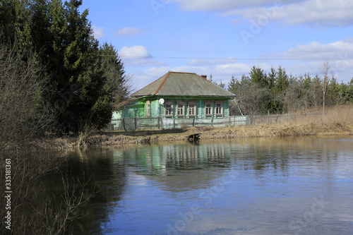 Landscape with old russian house on the pond