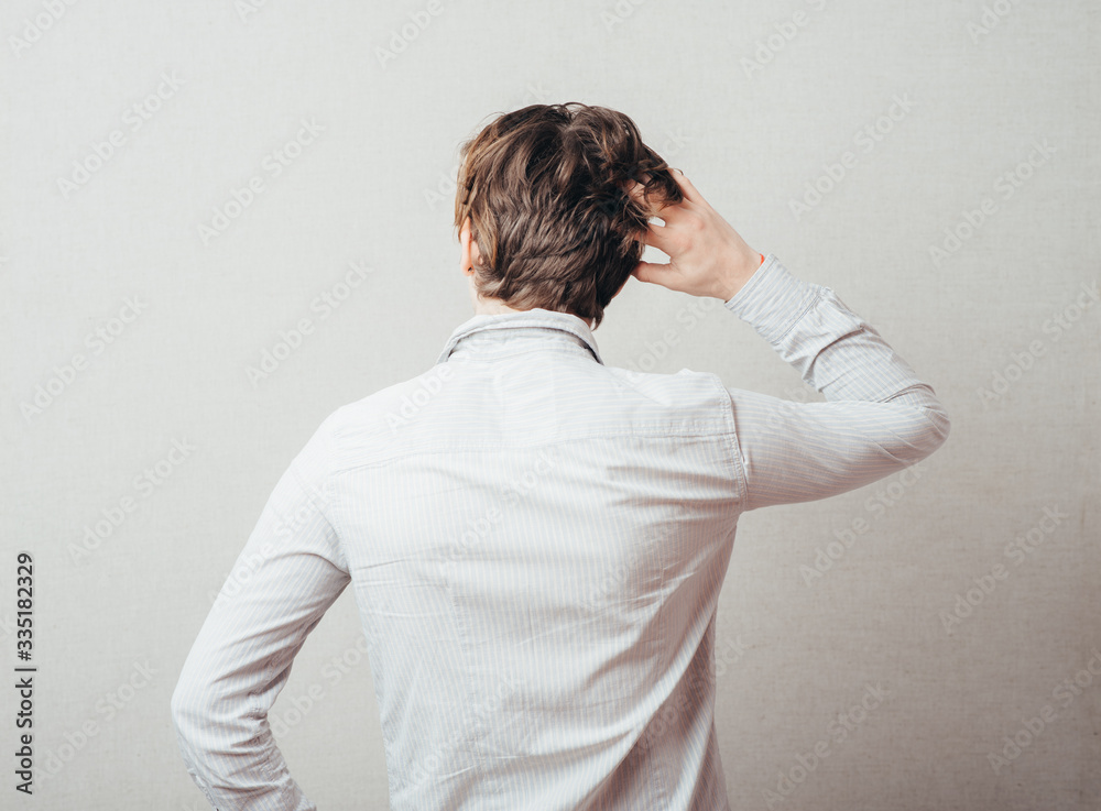 young man from the back scratching his head young man from the back scratching his head