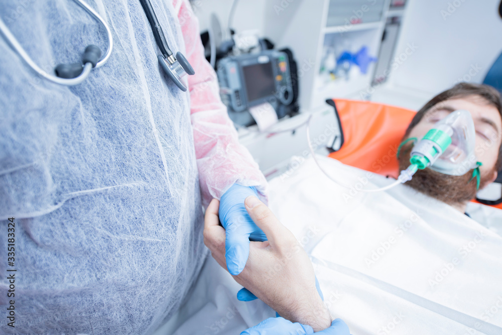 Ambulance interior, doctor with blue gloves takes hand to patient, while breathing oxygen. Emergency concept. Ambulance interior, doctor with blue gloves takes hand to patient, while breathing oxygen. Emergency concept.