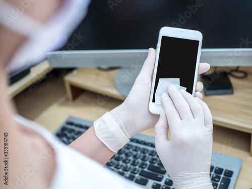 Asian women work at home using notebook, use alcohol pad to clean smartphone and prevent spreading of coronavirus during crisis of covid-19. Work from home and social distancing concept