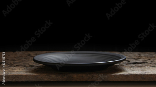Black plate on wooden black background.