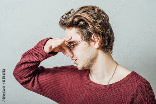 The man closed his nose on the stinky smell. On a gray background. photo