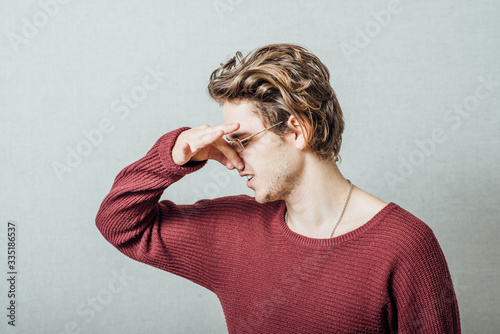 The man closed his nose on the stinky smell. On a gray background. photo