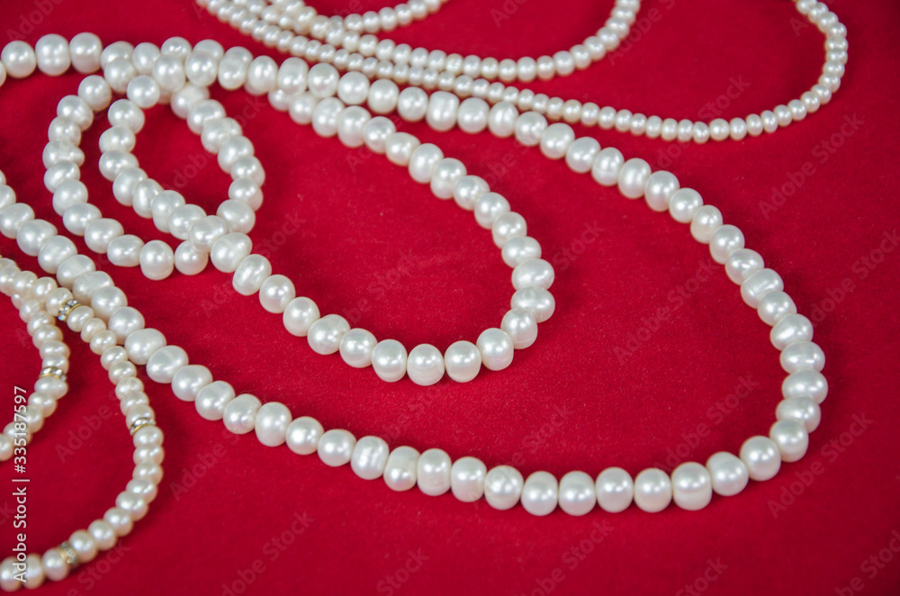 Beautiful white pearl necklaces on red floor