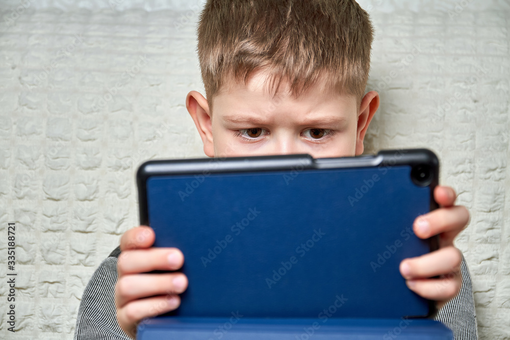 A boy playing with digital tablet at home. Quarantine. Stay at home.