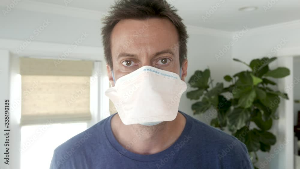 Man fits face mask on and then stares into the camera.