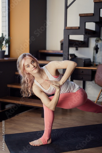 Beautiful athletic young modern girl goes in for sports at home. Yoga practice asana stretching meditation concentration relaxation stress, relief. parivritta parshvakonasana photo