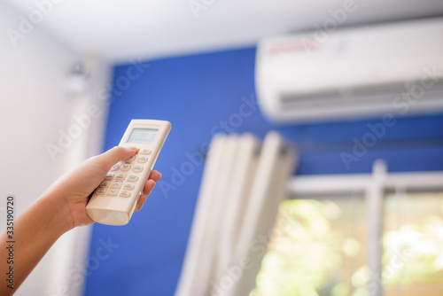 Woman is turning on air conditioner in home