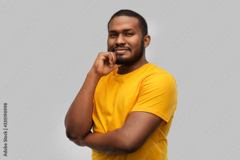 people concept - smiling young african american man in yellow t-shirt over grey background