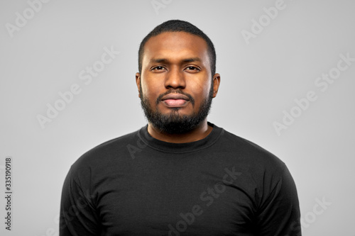 people concept - portrait of young african american man in black t-shirt over grey background